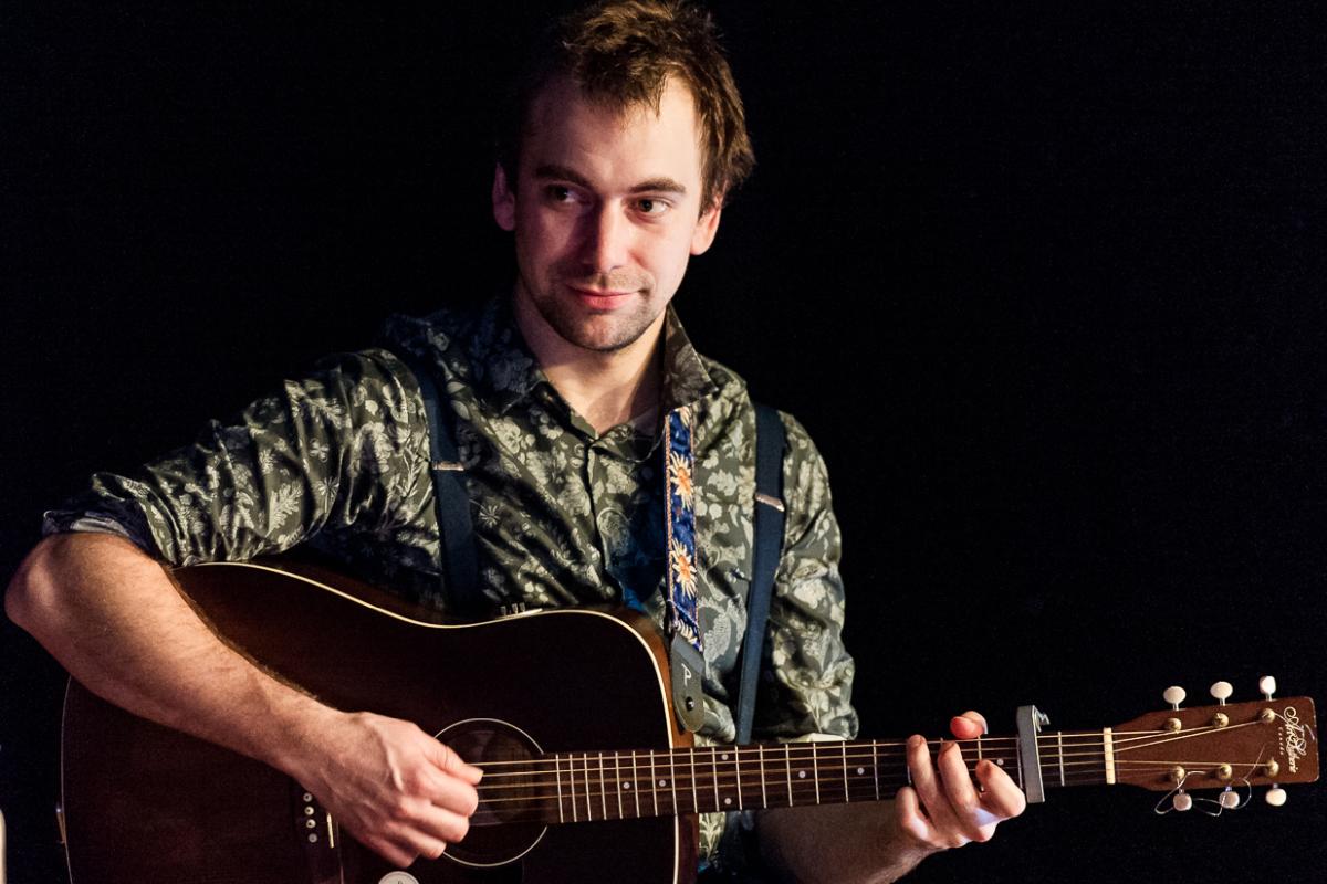 Brett playing fingerstyle guitar at a performance