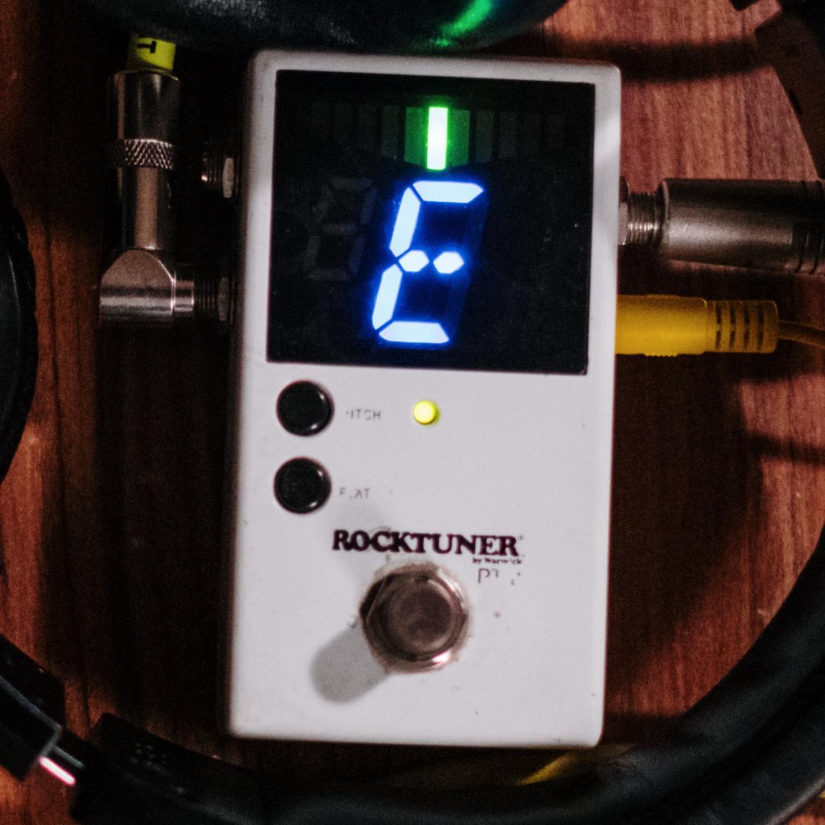 Electronic guitar tuner showing the note "E".