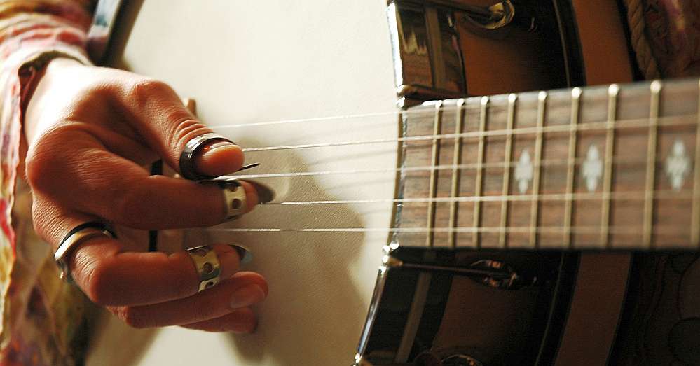 A woman using metal fingerpicks on the banjo
