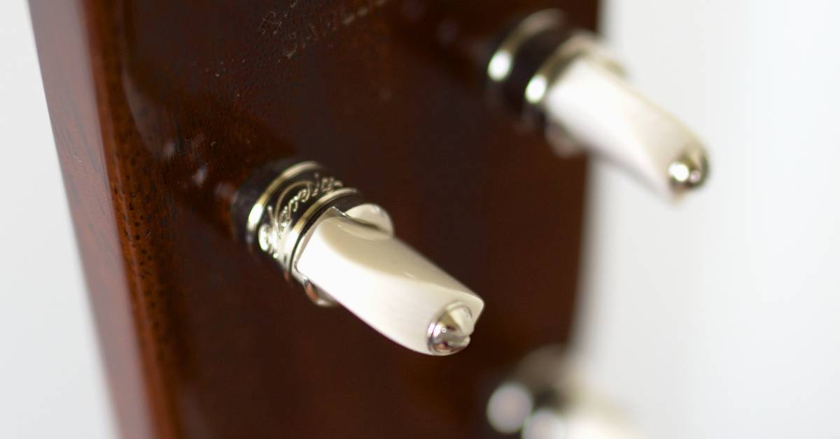 A close-up of friction peg tuners on a ukulele showing Laughlin 5-K