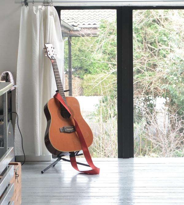 guitar in the corner with a strap