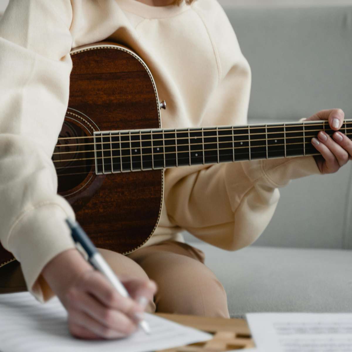 A girl playing guitar and writing with a pencil in an effective guitar practice session.